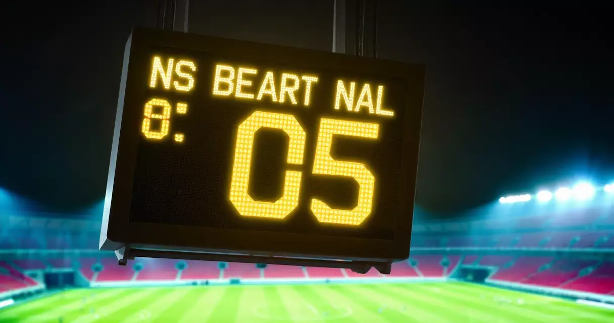 Stadium scoreboard showing Premier League result at night