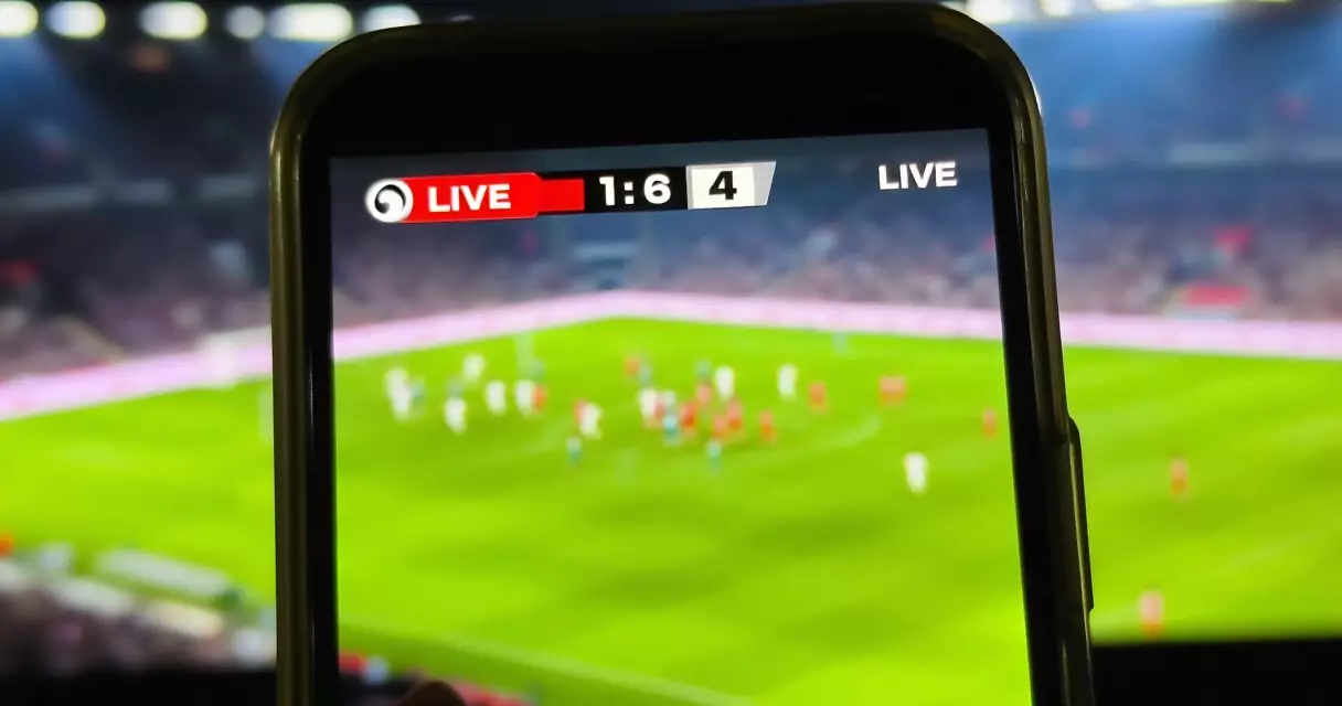 Smartphone showing a live Champions League scoreboard with a stadium behind it