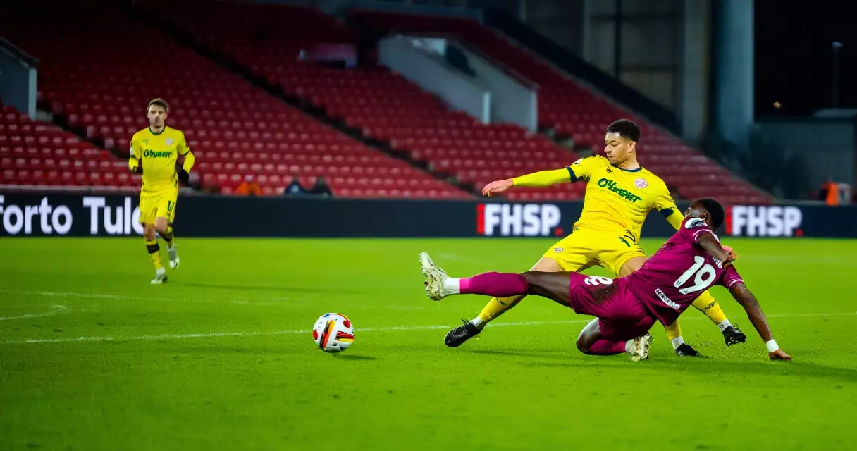 Football players competing for the ball in a floodlit Singapore stadium