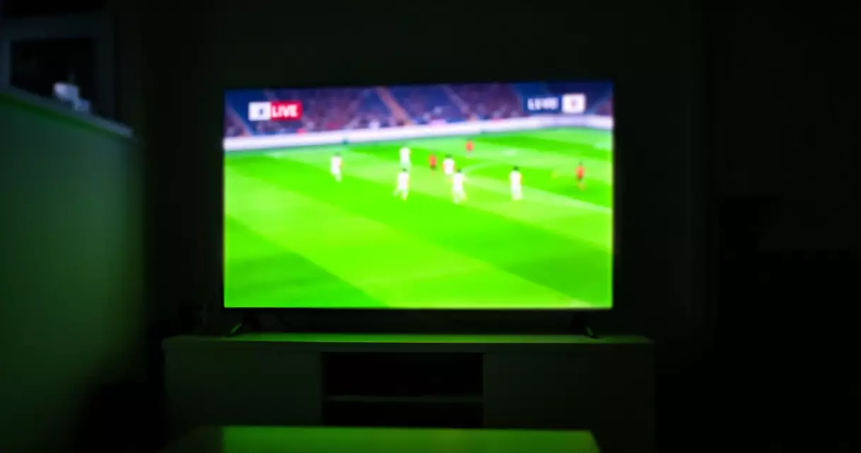 Television streaming a live Champions League match in a darkened living room