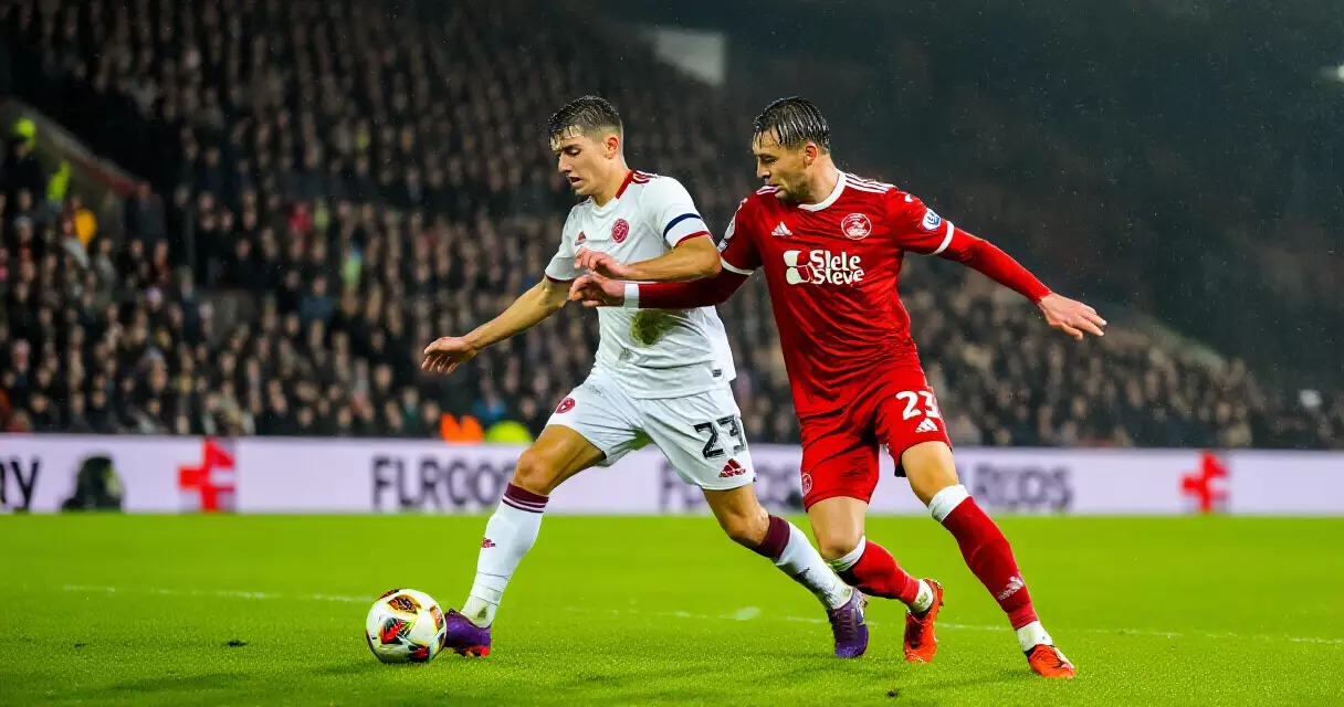Professional soccer players competing for the ball under stadium floodlights in a Premier League match