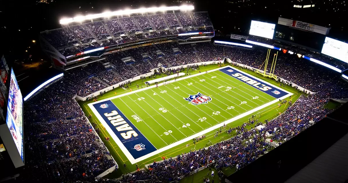 NFL stadium packed with fans at night, green field lit under stadium floodlights