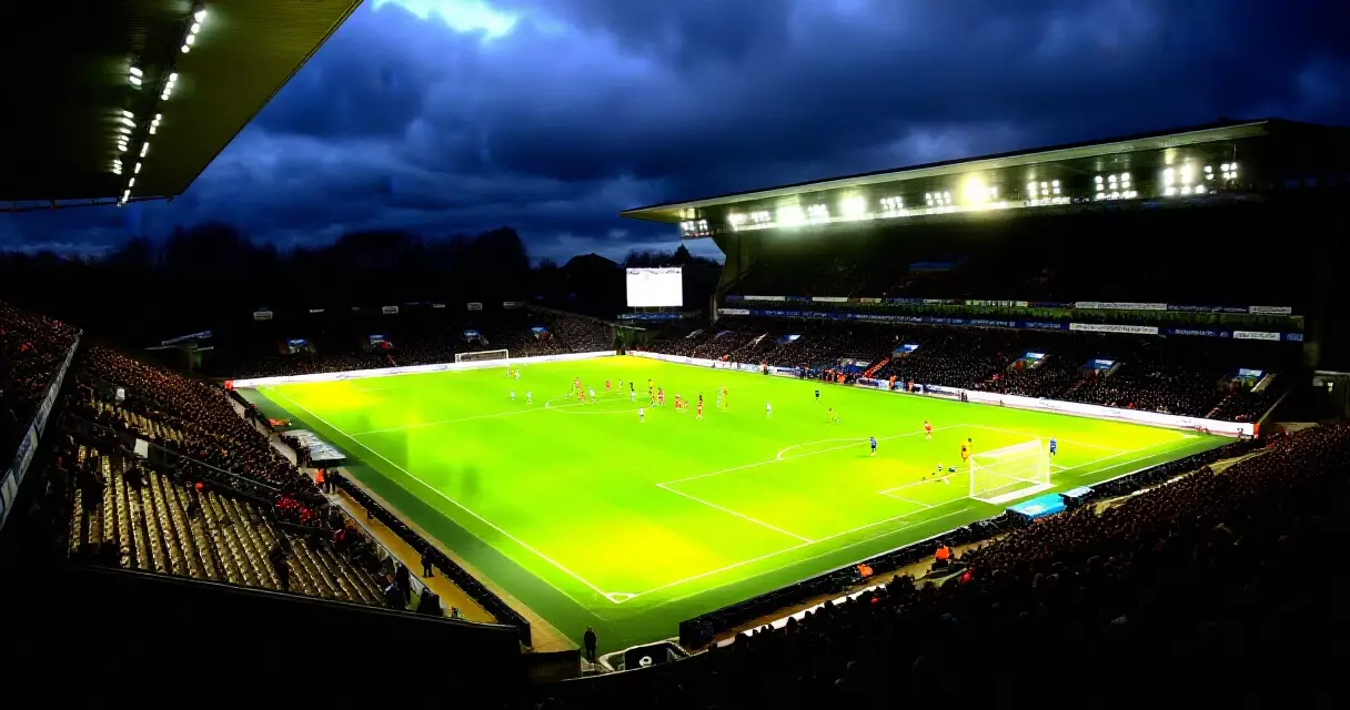 Premier League stadium lit up under floodlights during a Tuesday night midweek fixture