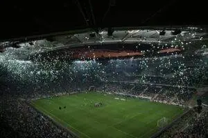 A crowded stadium at twilight with balloons filling the sky, creating a festive atmosphere.