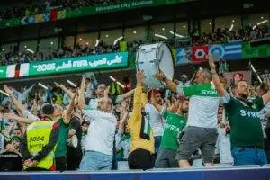 Cheering Syrian fans celebrate at the FIFA event in Doha, Qatar, showcasing lively support.