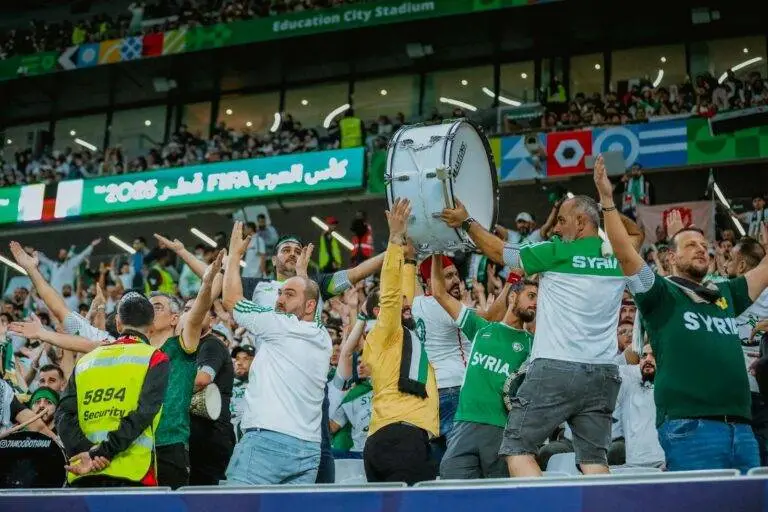 Cheering Syrian fans celebrate at the FIFA event in Doha, Qatar, showcasing lively support.