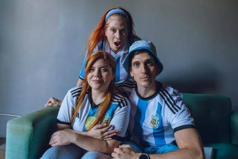 Group of fans in Argentina soccer jerseys expressing excitement indoors.